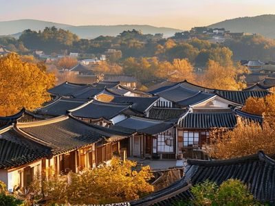 全州韩屋村传统韩式建筑群落，青瓦屋顶在秋日金色阳光下闪耀，游客身着韩服漫步其中