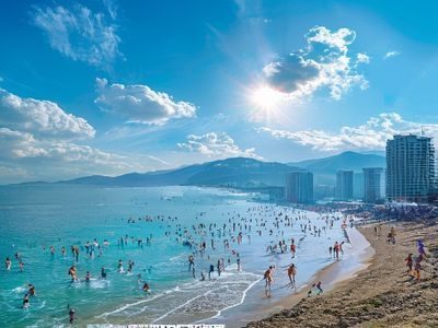 釜山海云台海滩阳光明媚，游客在碧蓝海水中嬉戏，背景是现代化高楼与蔚蓝天空